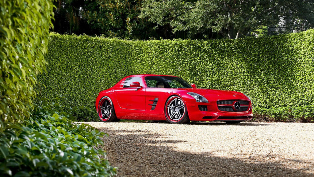 Vibrant Red Mercedes-Benz SLS AMG Wallpaper Against Lush Greenery
