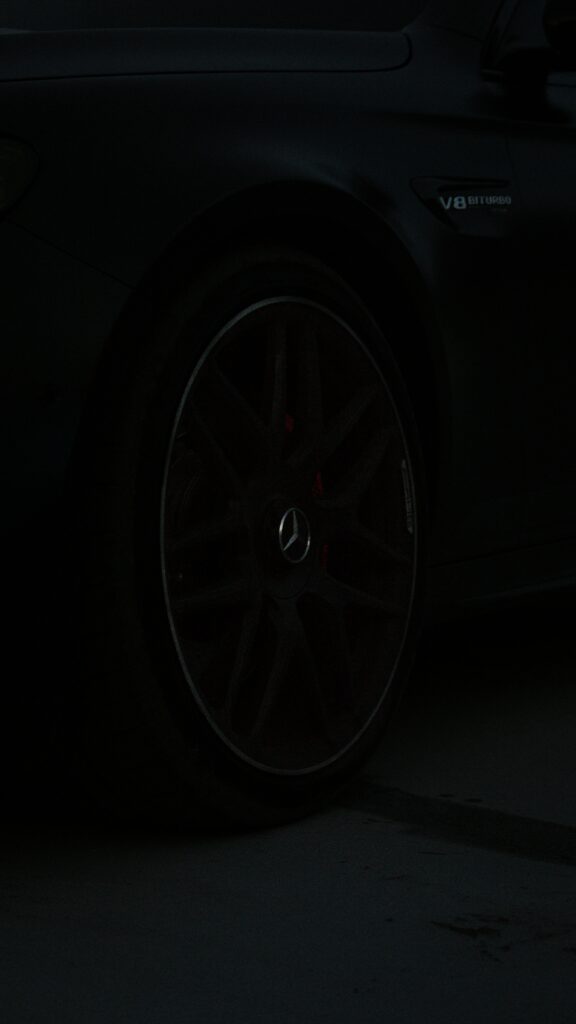 Close-up of Mercedes Benz V8 Biturbo black rim wheel luxury car dark background wallpaper