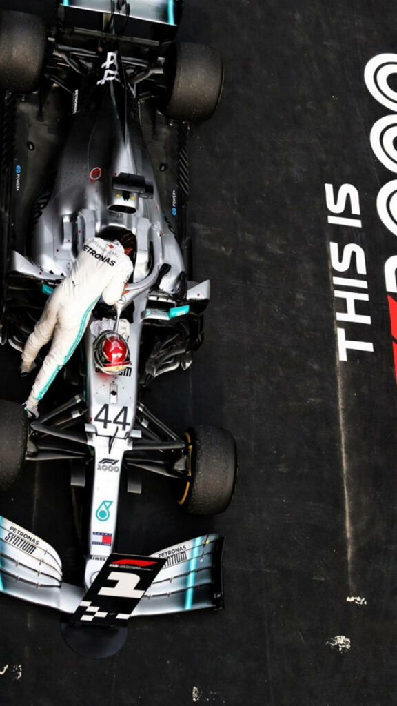Overhead view of Mercedes F1 driver entering sleek race car cockpit high speed racing wallpaper