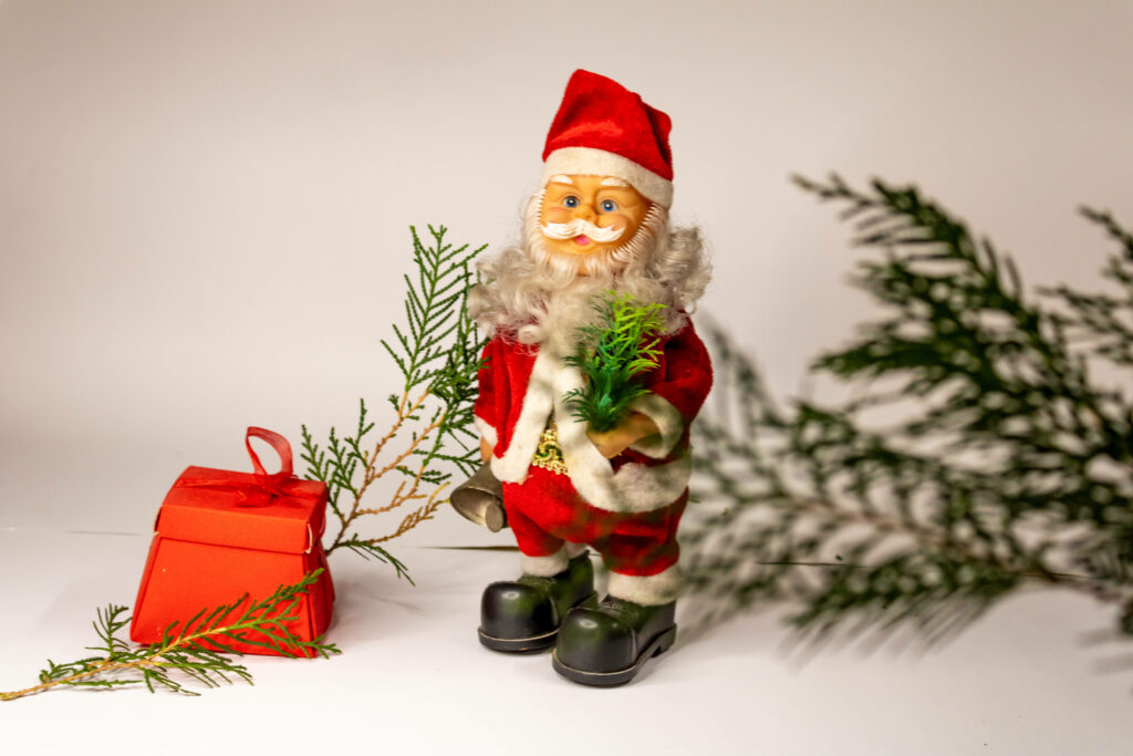 Festive Miniature Santa Claus Embracing Holiday Spirit with Adorable Gift Display Wallpaper