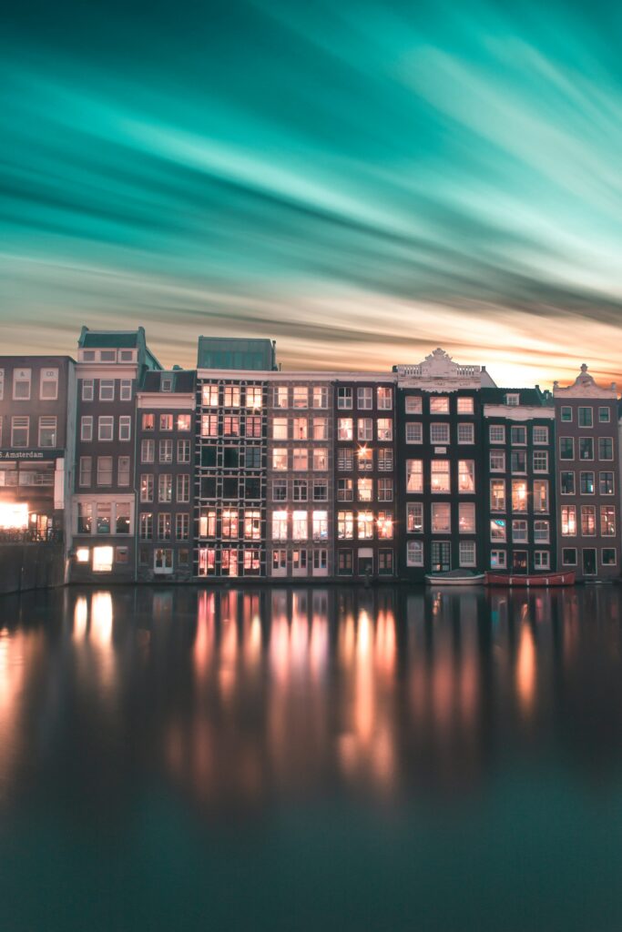Stunning Amsterdam Cityscape Wallpaper with Reflective Water & Gradient Sky