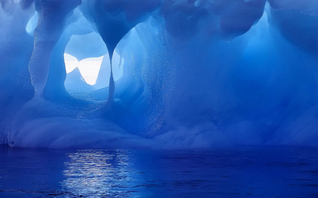 Vivid blue Antarctic ice cave with smooth sculpted walls reflected on calm glacier water wallpaper