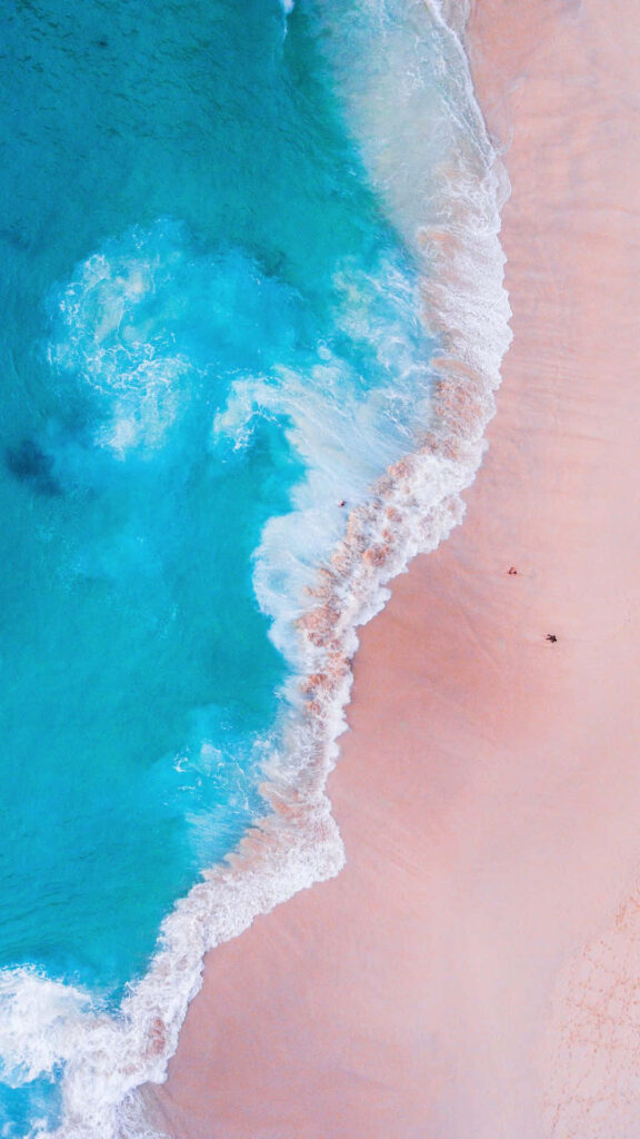 Enchanting Pink Sand Beach Wallpaper with Turquoise Waves Background