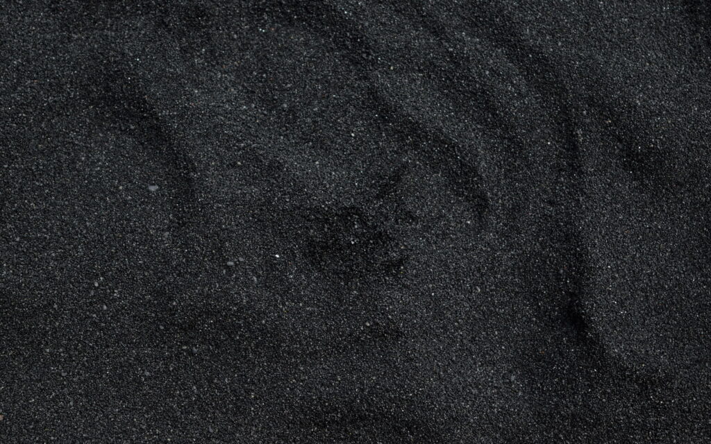 Macro 4K wallpaper of natural black sand textured volcanic dunes in moody monochrome tones