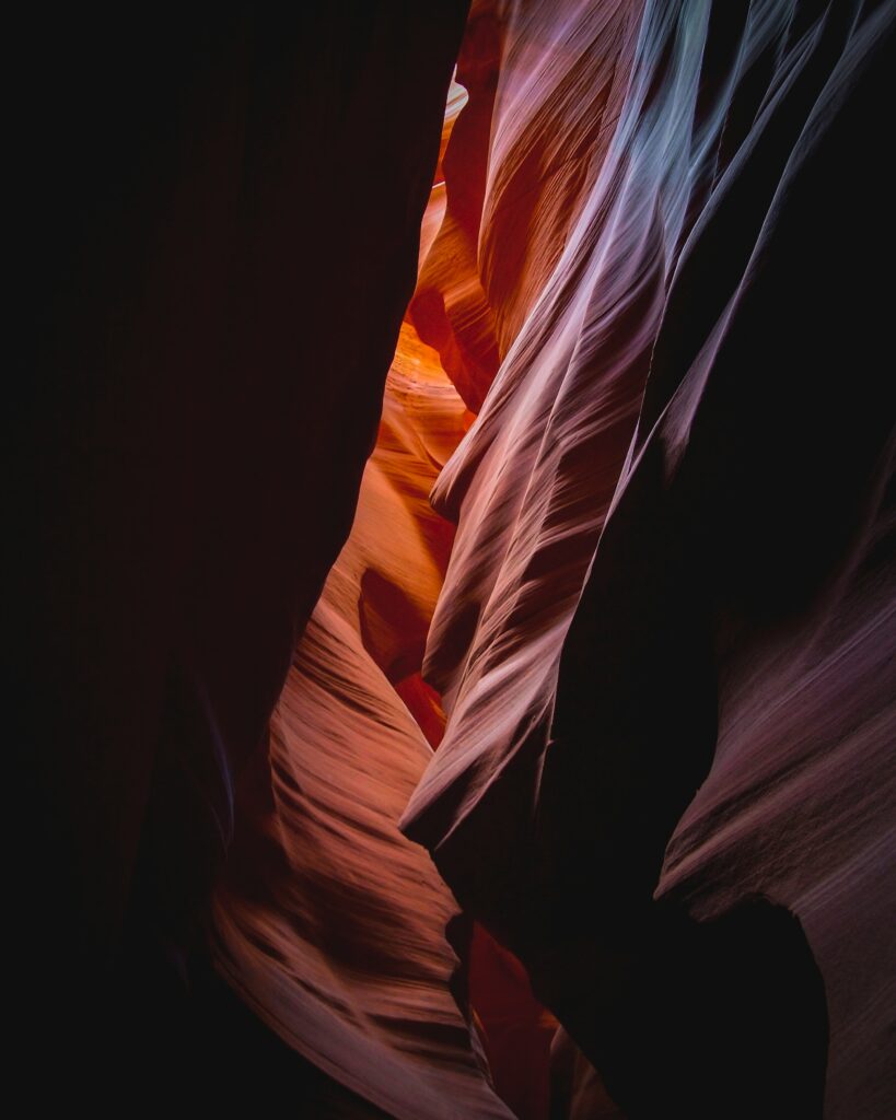 Dramatic canyon walls with warm light shafts highlighting textured rocky surfaces wallpaper
