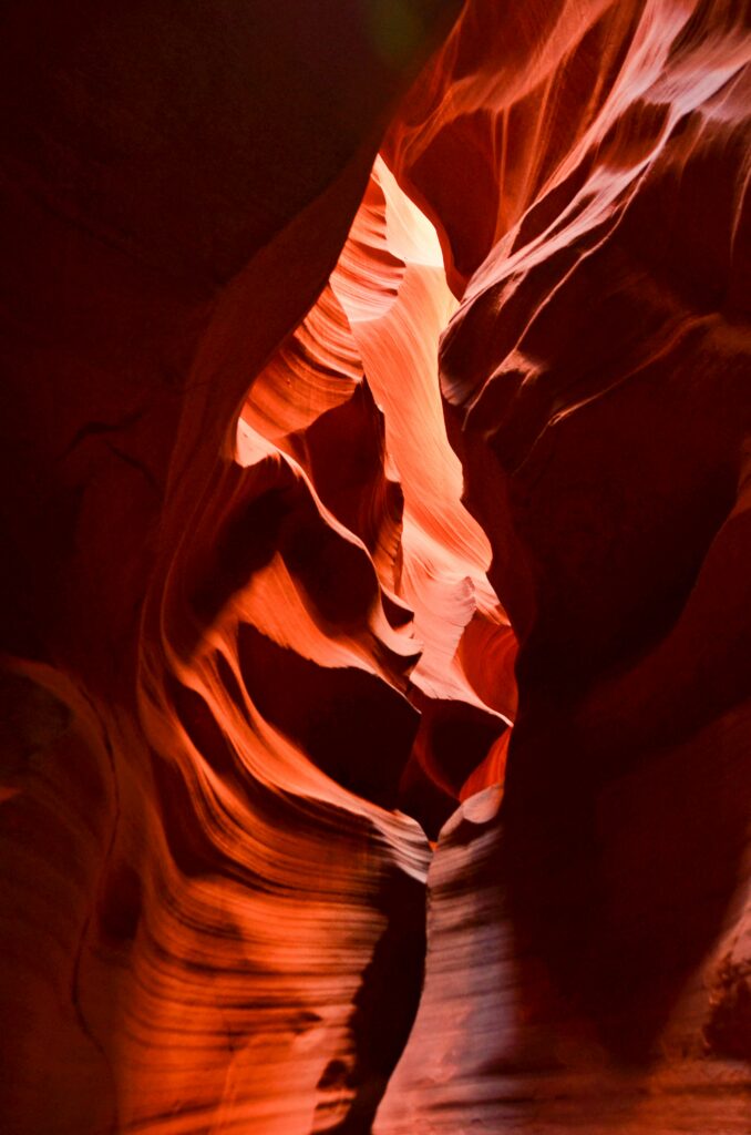 Sculpted cave rock formations with brown and red hues highlighted by natural light textures Wallpaper