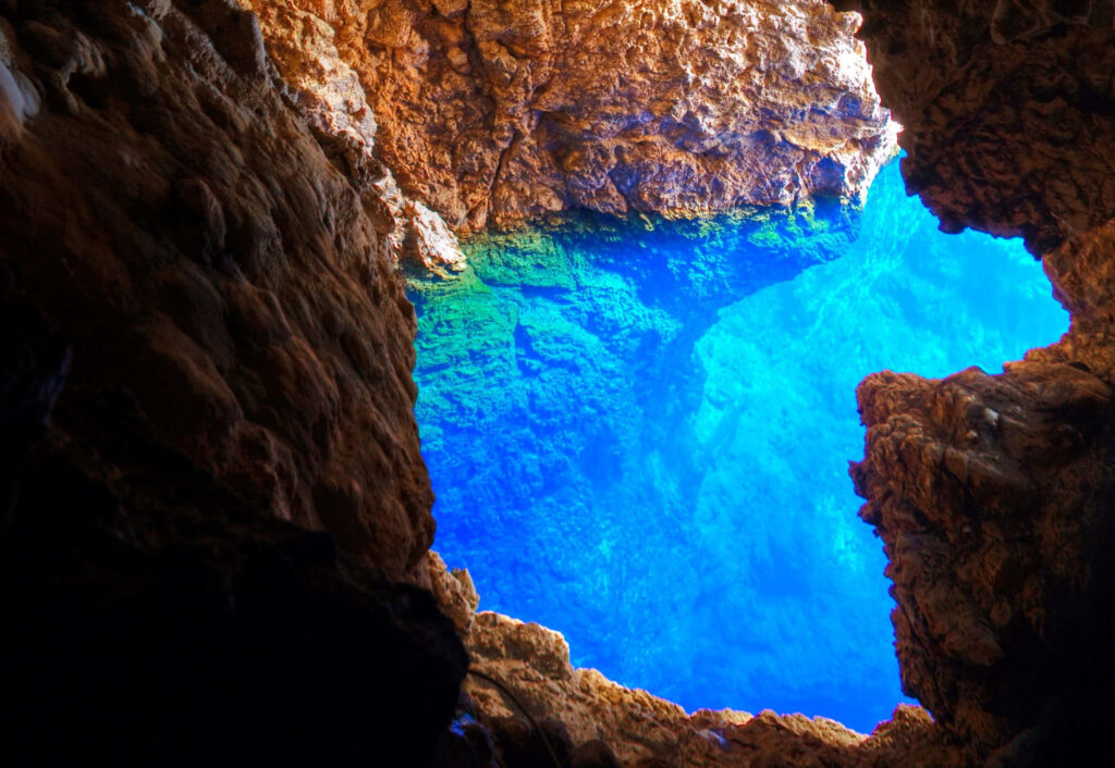 Mesmerizing Cave Interior Wallpaper: Rugged Rocks & Vibrant Blue Pool