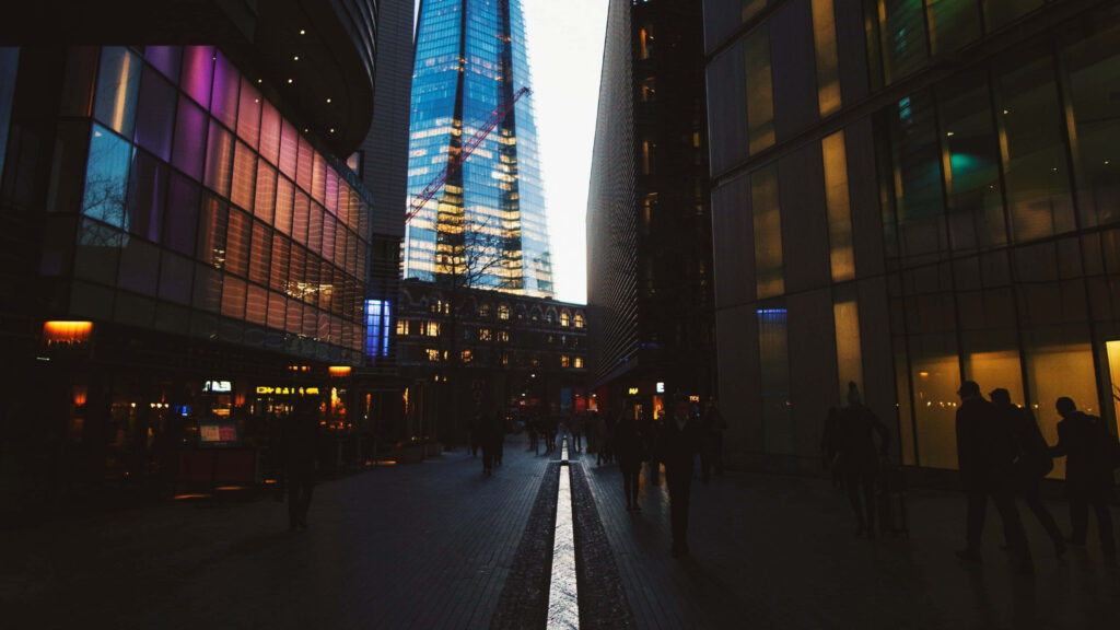 Night Cityscape Wallpaper: Illuminated Glass Building & Bustling Streets