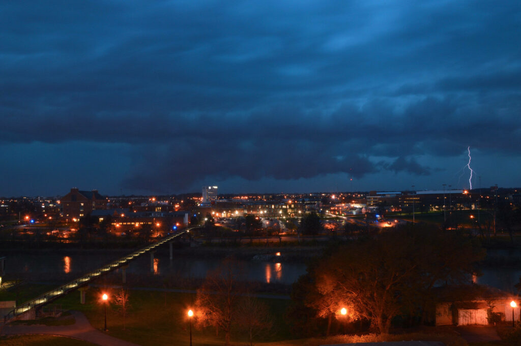 Stunning Columbus Cityscape: Cloudy Evening with Lightning & River Reflection Wallpaper