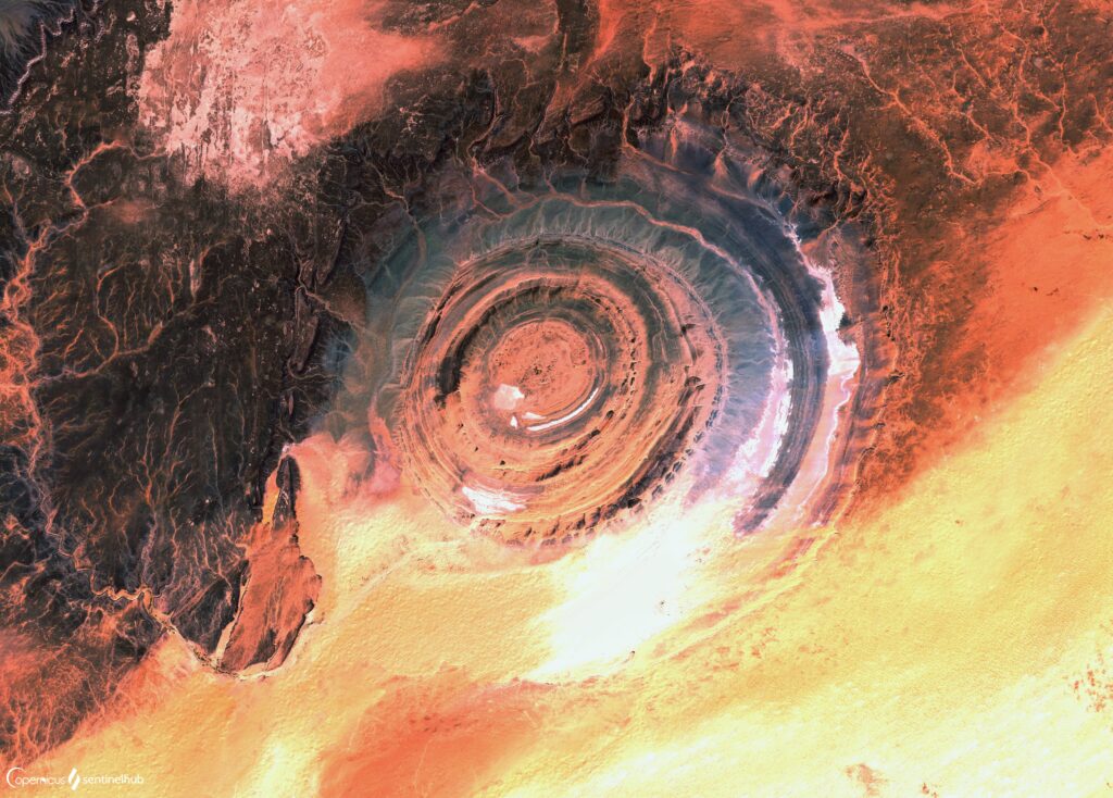 Aerial view of desert landscape with swirling sand formations and concentric rings in brown tones Wallpaper