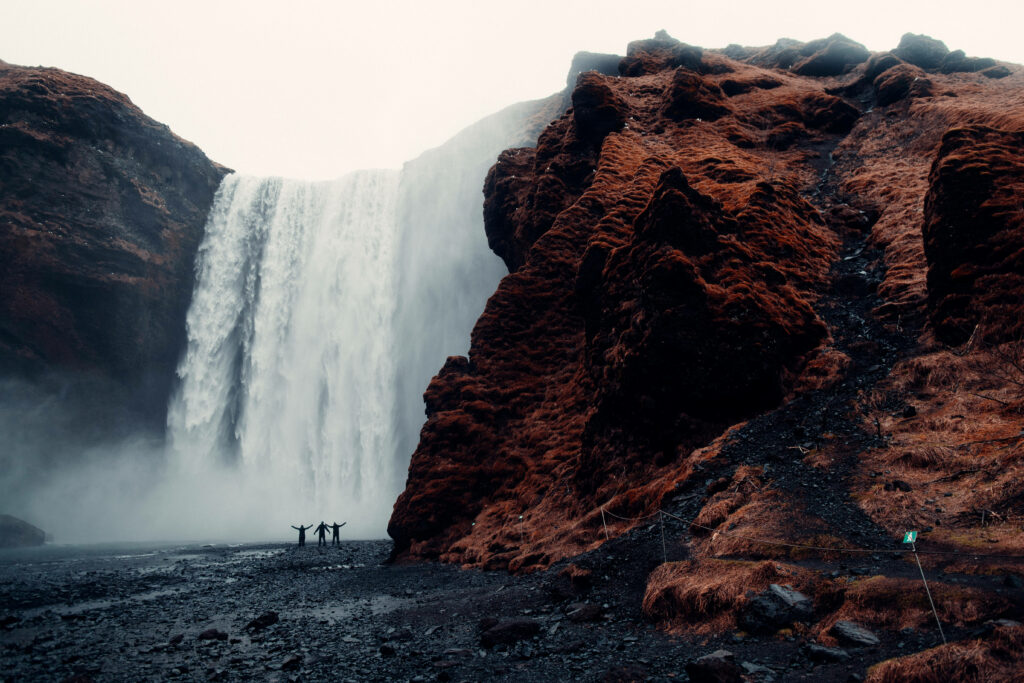 Thrilling Encounter: Three Adventurous Men Conquer the Majestic Waterfall - Mesmerizing 4K HD Laptop Background Wallpaper