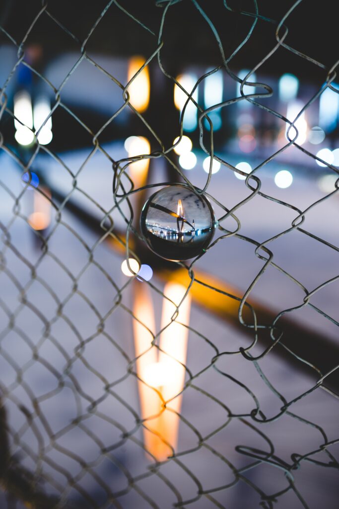 Artistic Wallpaper: Glass Ball on Metal Fence Reflecting City Lights
