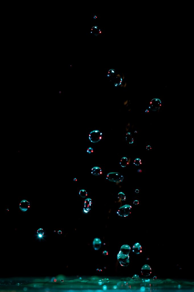 Glowing Water Drops Splash Wallpaper: Mesmerizing Dark Background