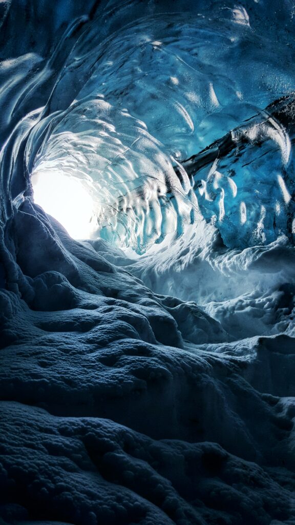 Mesmerizing Icelandic ice cave interior with blue ice textures and natural light illumination Wallpaper