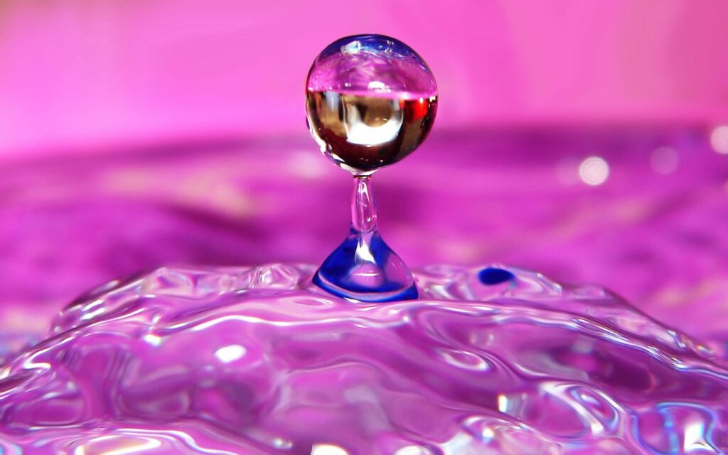 Vibrant Liquid Droplet Wallpaper: Mid-Motion with Pink & Purple Hues