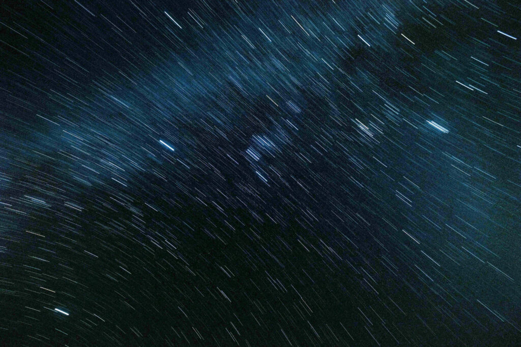 Long-exposure night sky capturing mesmerizing star trails in a cosmic wallpaper background.