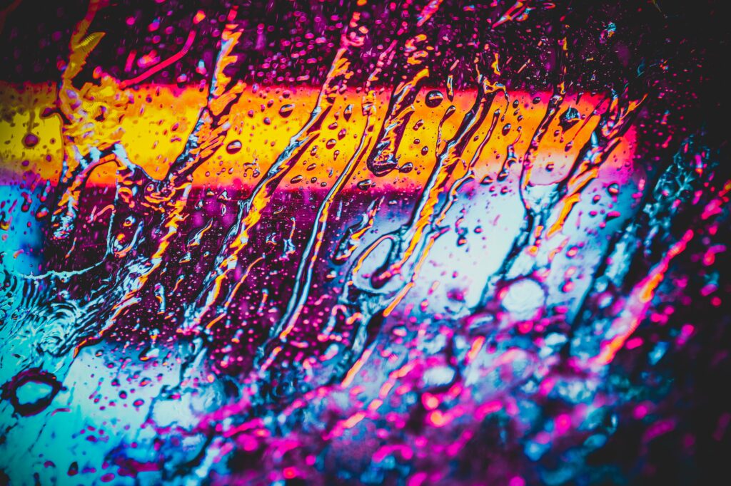 Neon Water Droplets on Glass: Vibrant Rainy Wallpaper Background