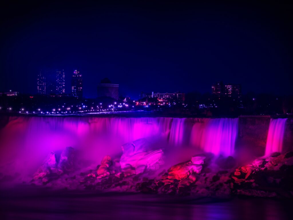 Enchanted Night Cityscape Wallpaper with Glowing Waterfall