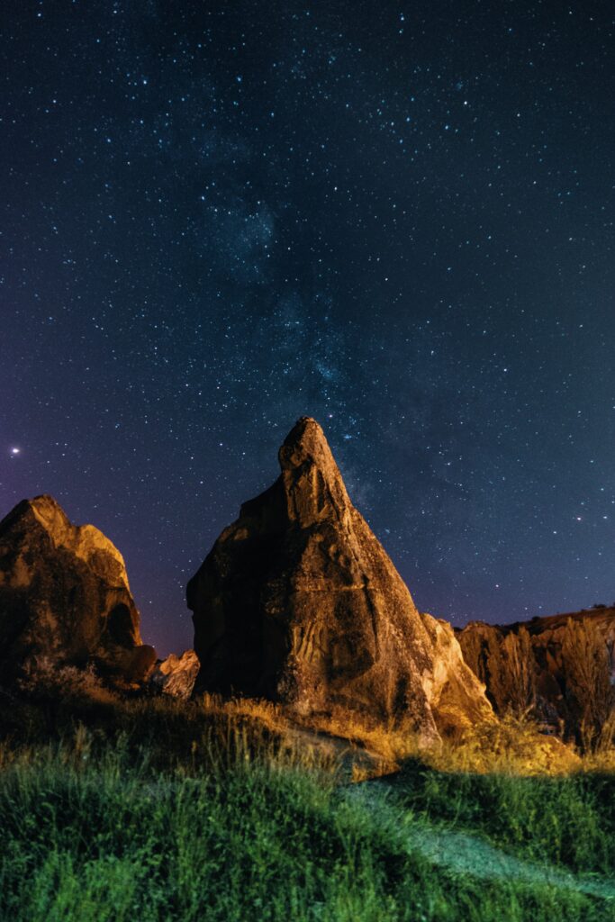Rugged stones under a vibrant starry night sky with soft lighting serene natural landscape wallpaper