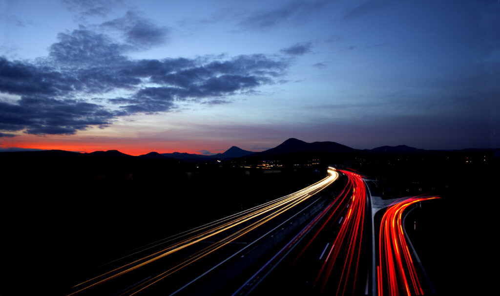Twilight Road Wallpaper: Streaks of Light & Mountain Silhouettes