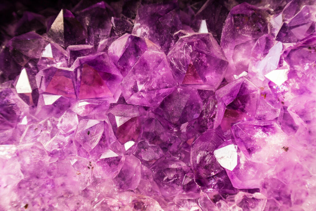 Close-up of vibrant purple amethyst crystal cluster with natural geometric facets wallpaper background