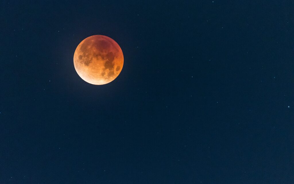 Mesmerizing Full Moon Wallpaper: Reddish Hue Against Starry Sky
