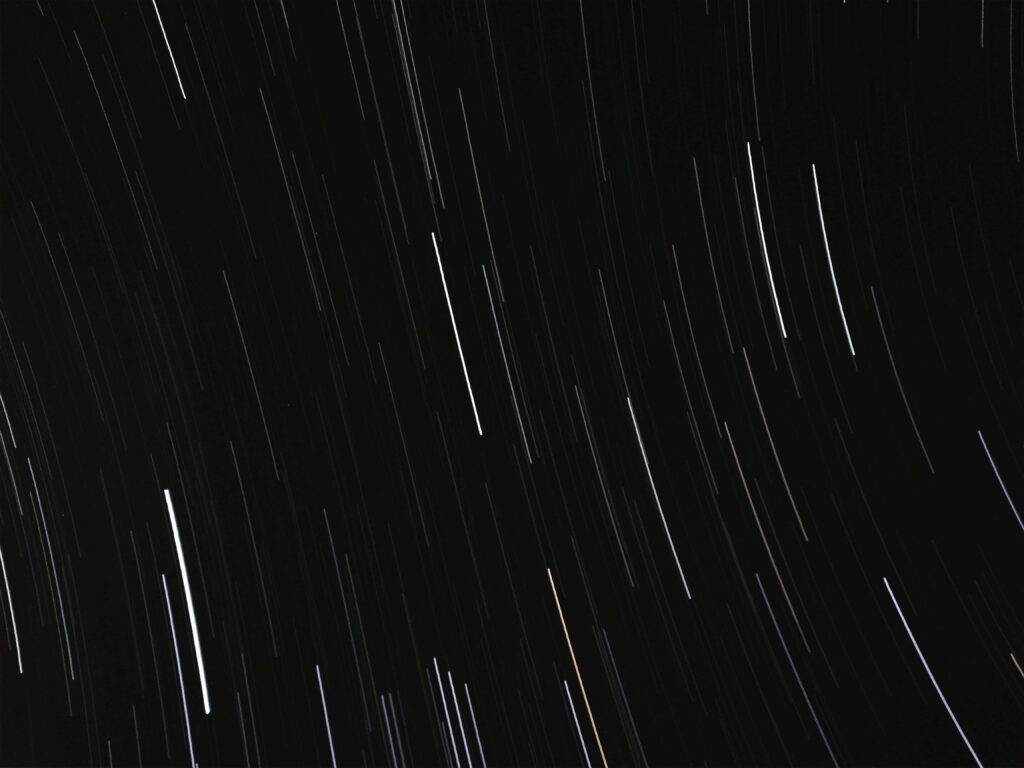 Stunning night sky wallpaper with star trails illustrating Earth's rotation and celestial arcs.