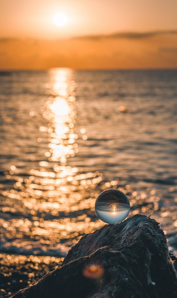 Serene Sunset Over Sea: Captivating Glass Ball Reflection Wallpaper