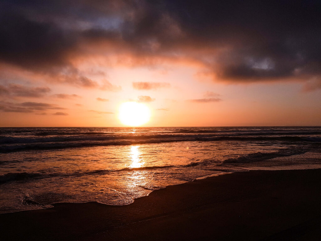 Tranquil Sunset Over Ocean Waves: Warm Golden Glow Background Wallpaper