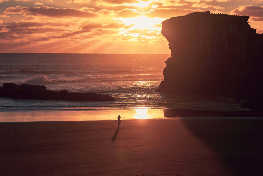 Golden Sunset Over Serene Beach with Silhouetted Figure Wallpaper