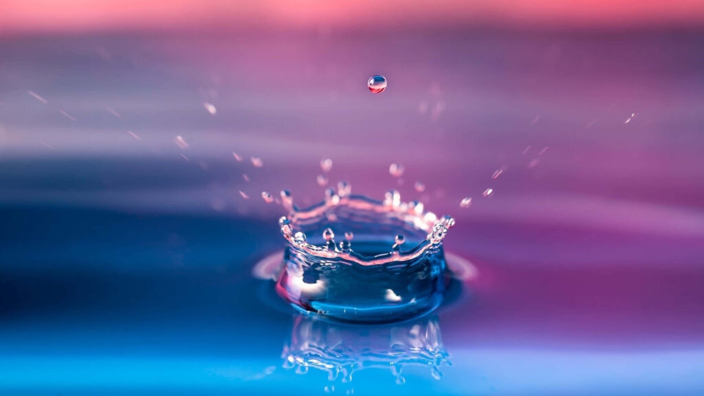 Stunning Water Droplet Splash on Vibrant Blue and Pink Background Wallpaper