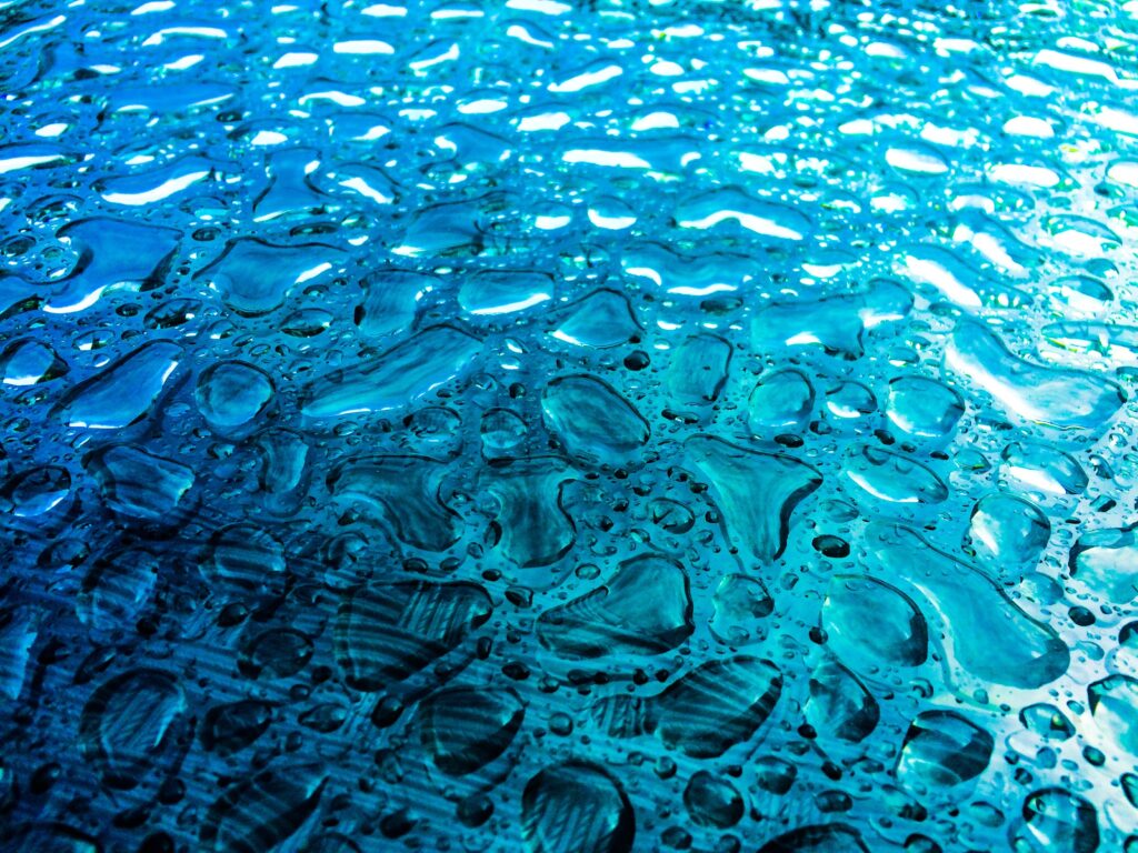 Mesmerizing Blue Water Drops Wallpaper Background on Textured Surface
