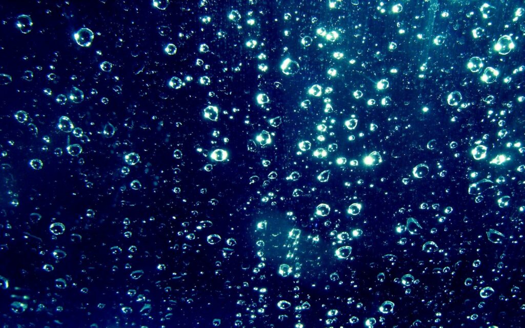 Serene Water Drops Wallpaper: Soft Blue Glow on Dark Surface
