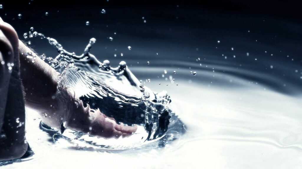 Mesmerizing Water Splash Wallpaper: Close-Up Finger Interaction