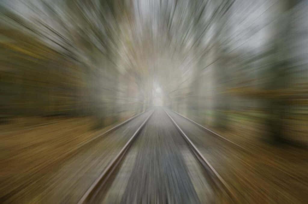 Forest Frenzy: Racing Towards the Light on Speeding Train Tracks Wallpaper
