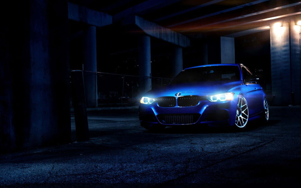 Metallic blue BMW 335i under overpass with dramatic lighting showcasing sleek design wallpaper