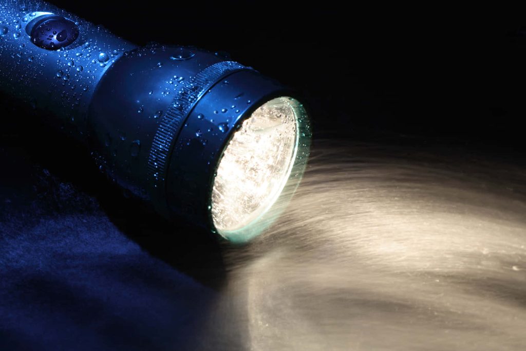 Metallic blue flashlight glowing bright white beam in dark wet close-up modern wallpaper background