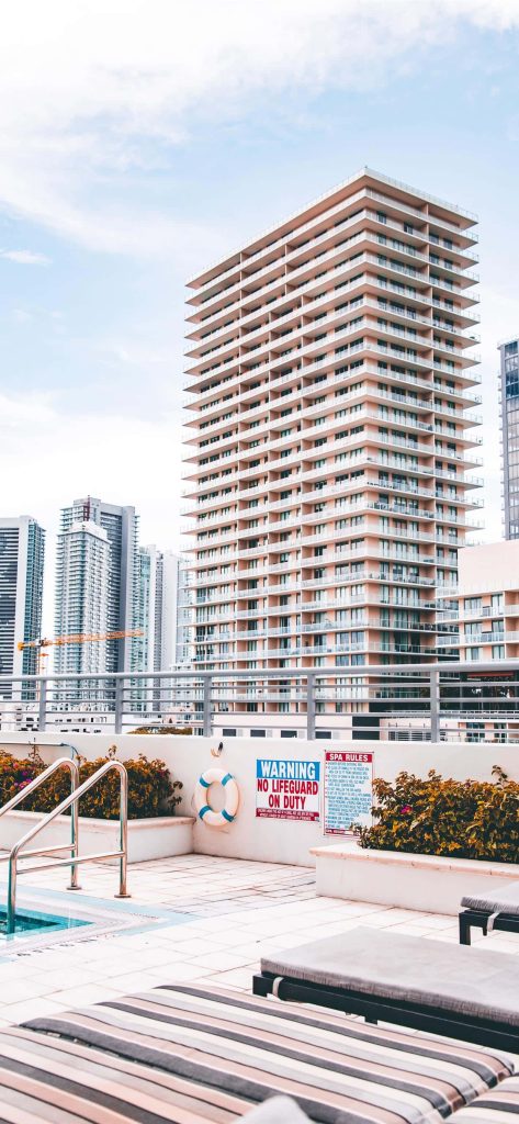 Miami rooftop pool deck wallpaper with lounge chairs lifebuoy and city skyscrapers background