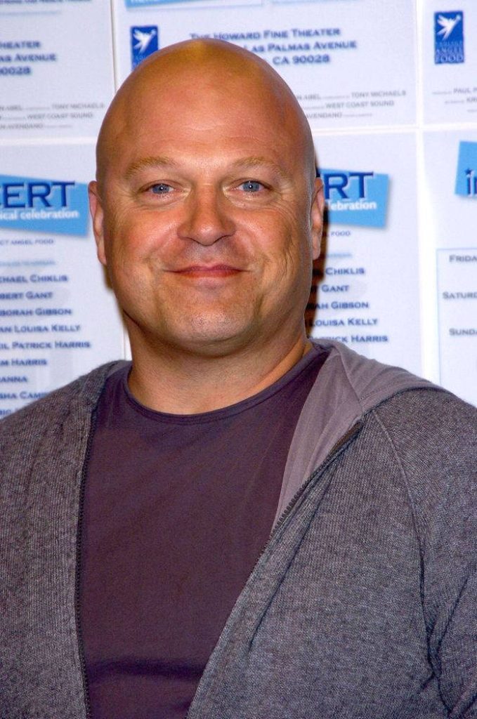 Michael Chiklis smiling in grey hoodie bright event lighting blurred media wall background Wallpaper