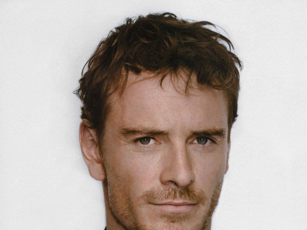Close-up portrait of Michael Fassbender with messy brown hair and light scruff studio background Wallpaper