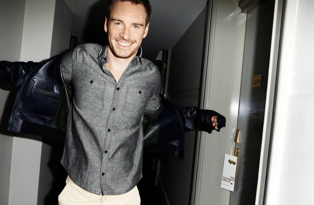 Michael Fassbender smiling in hotel hallway by room LG14 wearing grey shirt and jacket background Wallpaper