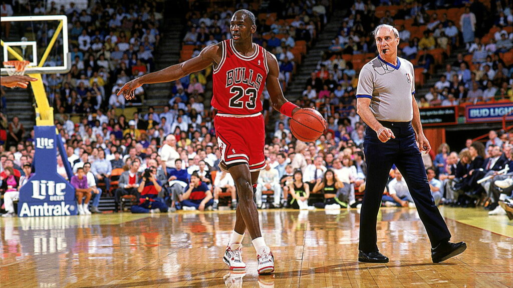Michael Jordan dribbling basketball in red Chicago Bulls jersey number 23 during NBA game Wallpaper