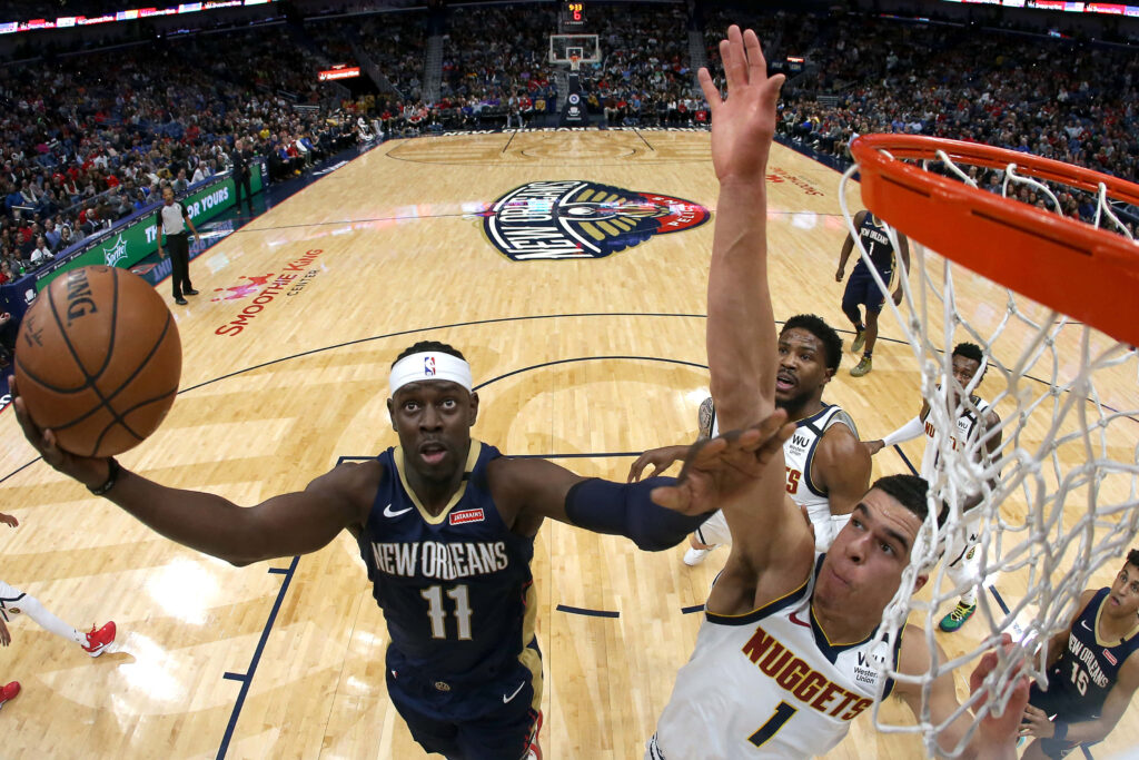 Michael Porter Jr. leaping to block New Orleans Pelicans player on vibrant NBA basketball court Wallpaper