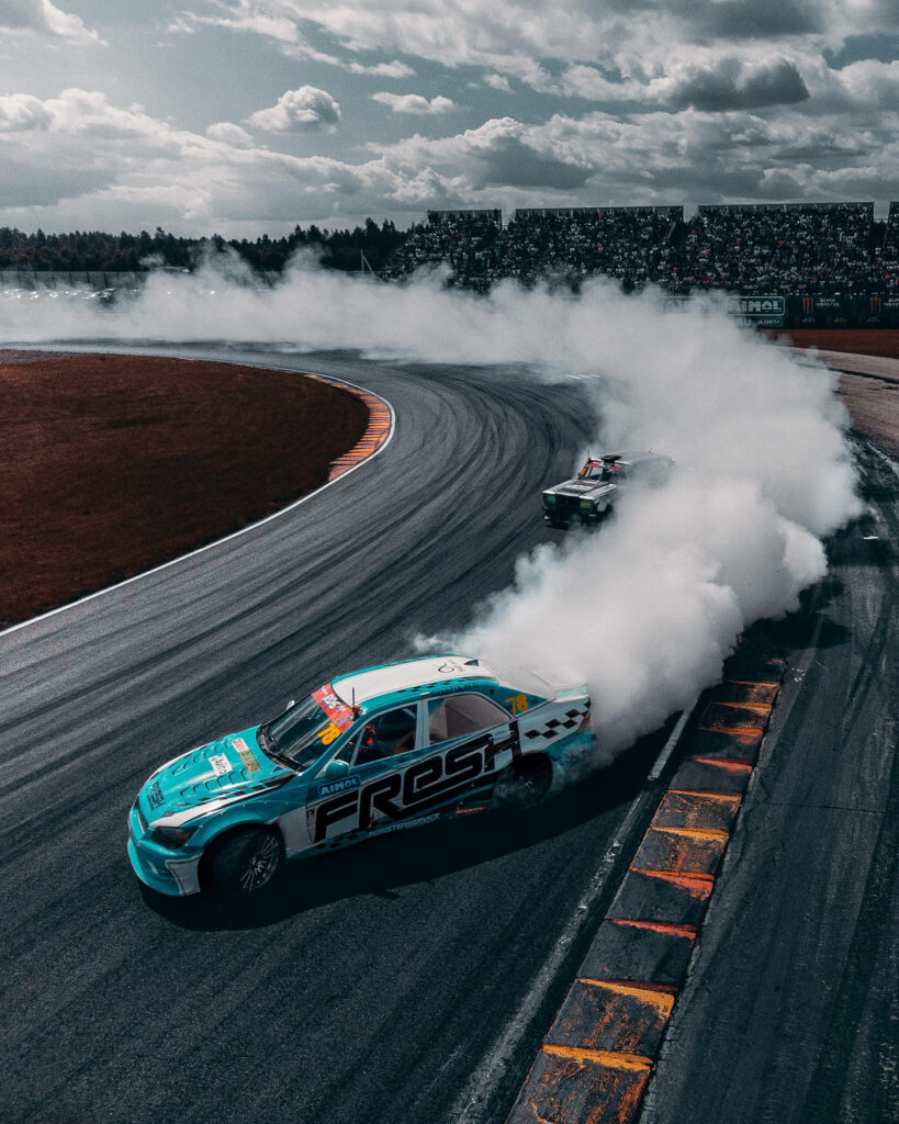 Vibrant drift car racing through smoky bend on dramatic track under moody midnight skies wallpaper