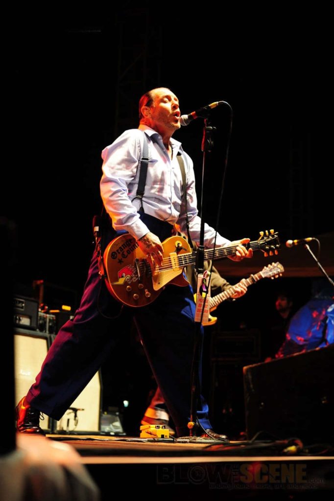Mike Ness performing live with sticker-covered guitar under warm stage lights punk rock wallpaper