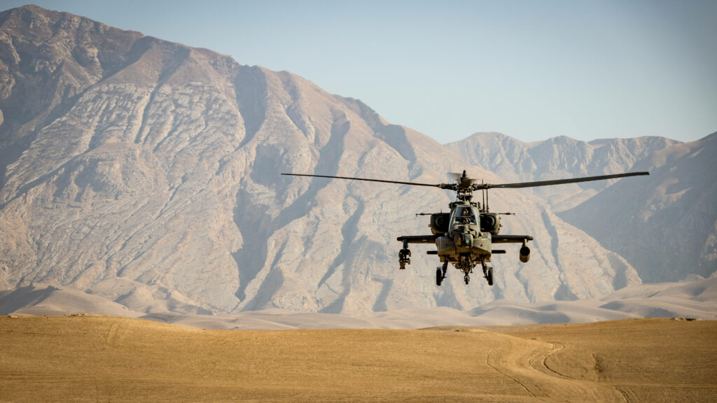 Military helicopter landing on sandy Afghanistan terrain with rugged mountains background wallpaper