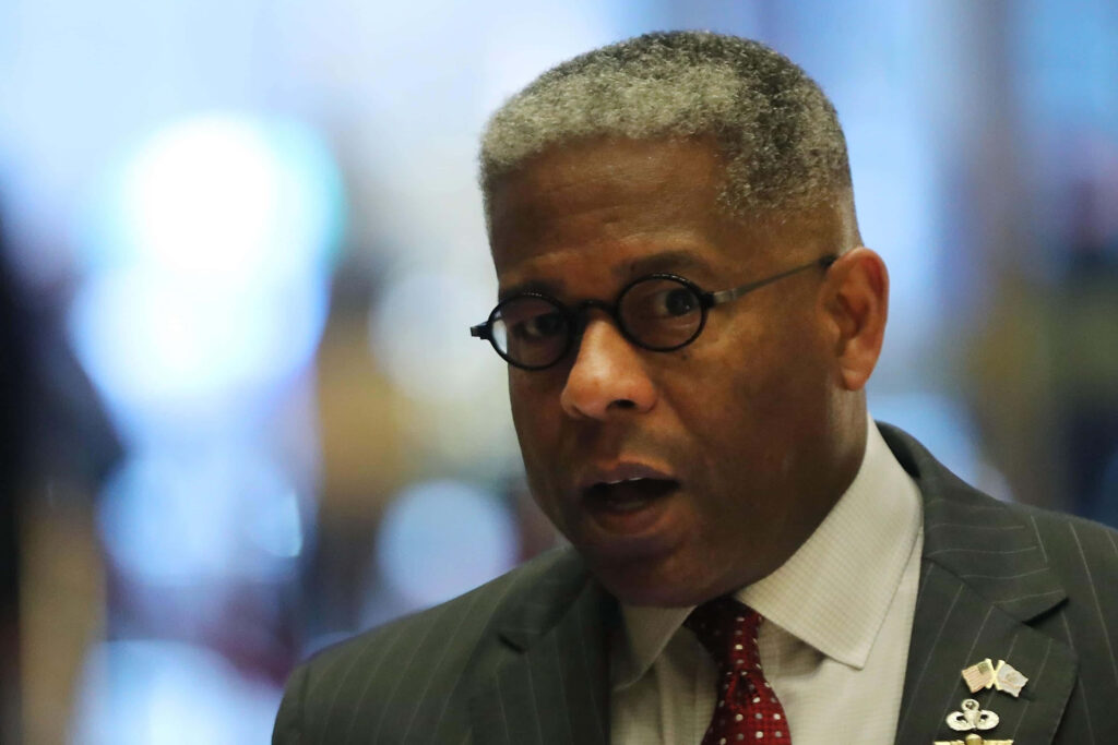 Military Officer Allen West in formal suit and glasses standing confidently in professional setting wallpaper