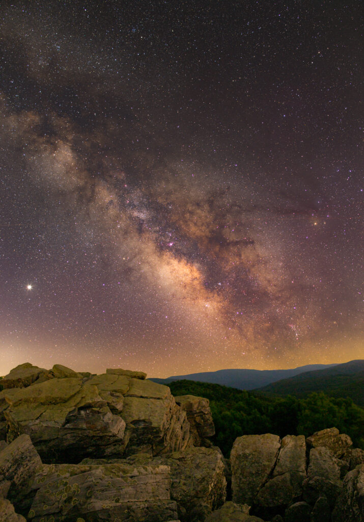 Milky Way arching over rocky terrain and hills under a star-filled clear night sky wallpaper
