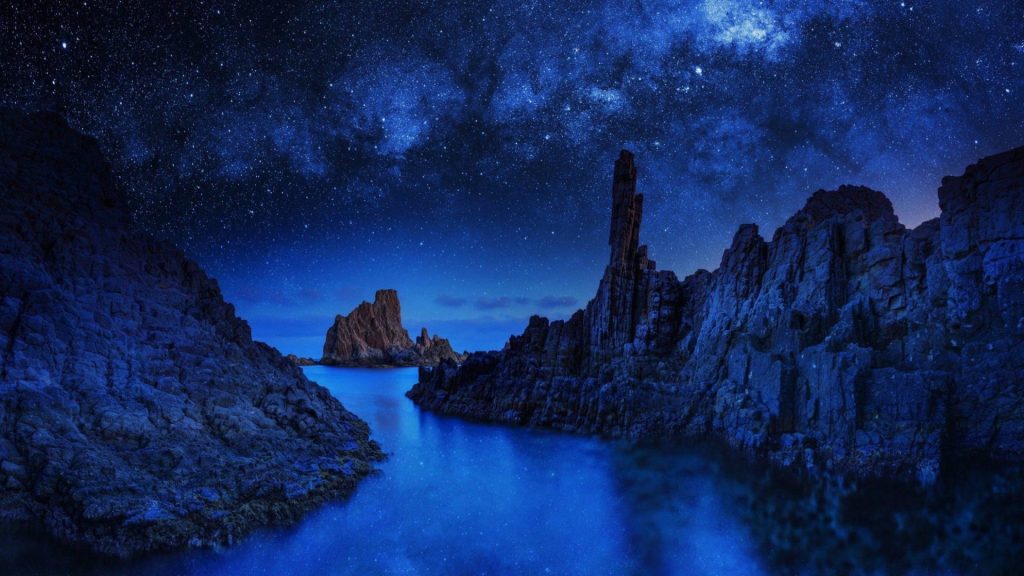 Milky Way over Bombo Quarry with basalt cliffs sea stack and calm blue waters at night Wallpaper