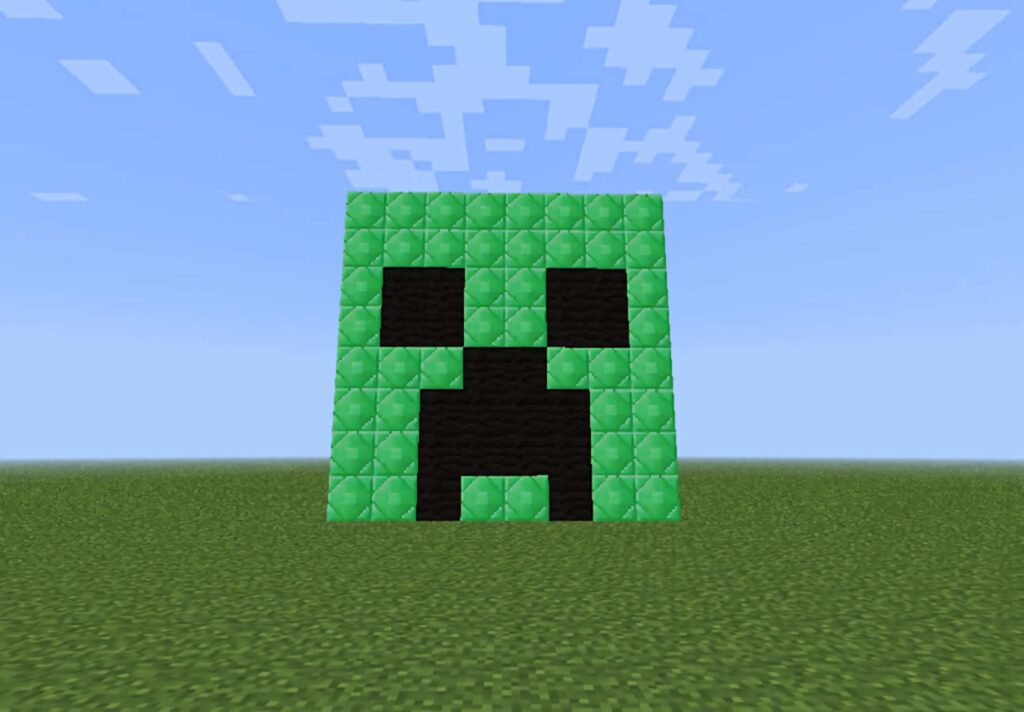 Pixelated Minecraft Creeper face made of green black blocks on grassy landscape with blue sky Wallpaper